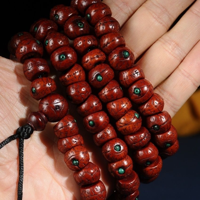 Phoenix eye bodhi beads with turquoise colored inlay shown in hand