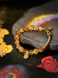 Bracelet with amber-colored beads and gold accents on a decorative surface