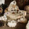 Clear beaded bracelet on a wooden surface with crystals and pinecones