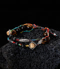 Woven tiger eye and seed bead bracelet shown on dark textured background