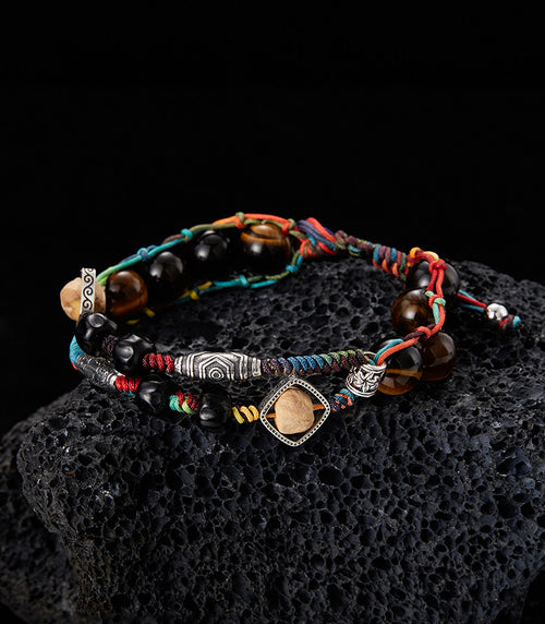 Woven tiger eye and seed bead bracelet shown on dark textured background