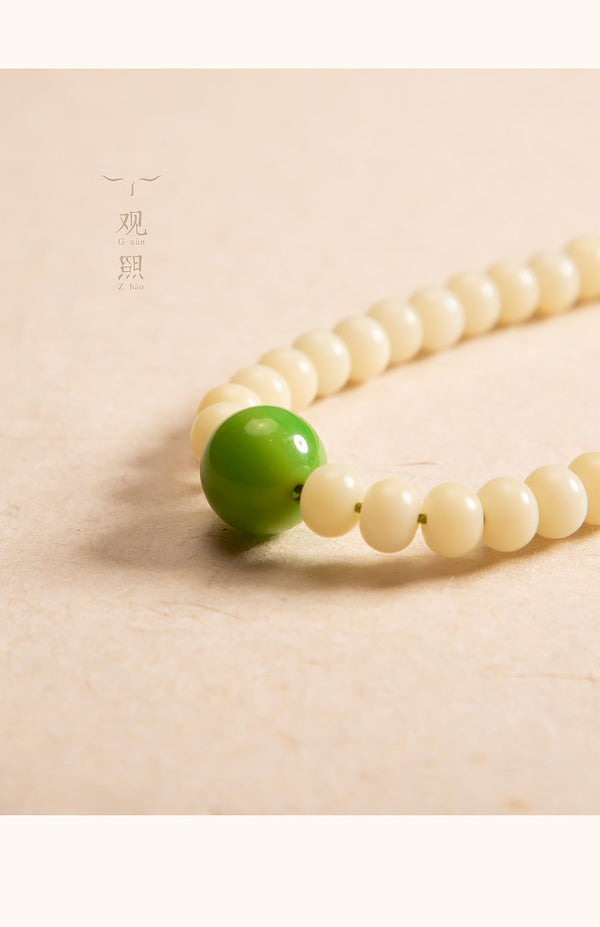 Close detail of white bodhi beads and green accent bead