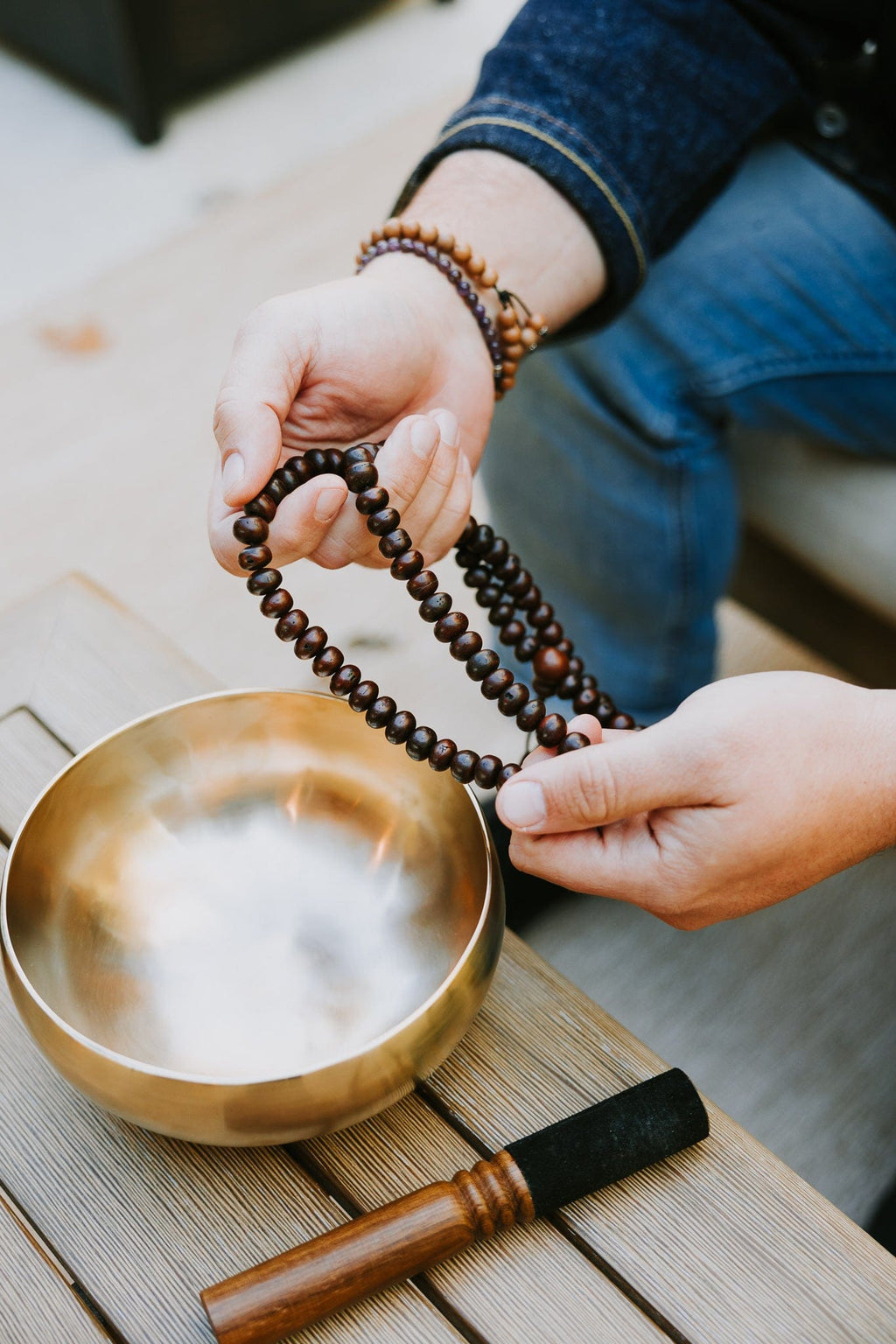 Dark bodhi seed mala held beside a singing bowl