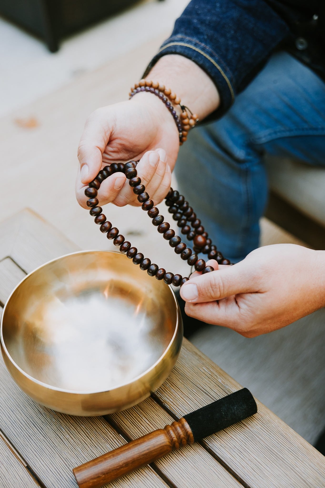 Dark bodhi seed mala held beside a singing bowl