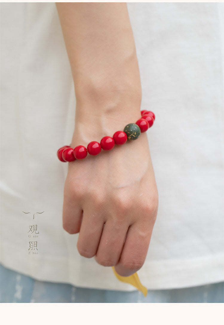 Red glass Tibetan-style bracelet on wrist with green accent bead
