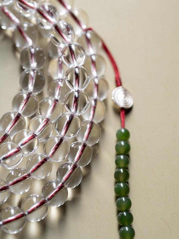 Close view of clear white crystal mala beads with red and white cord