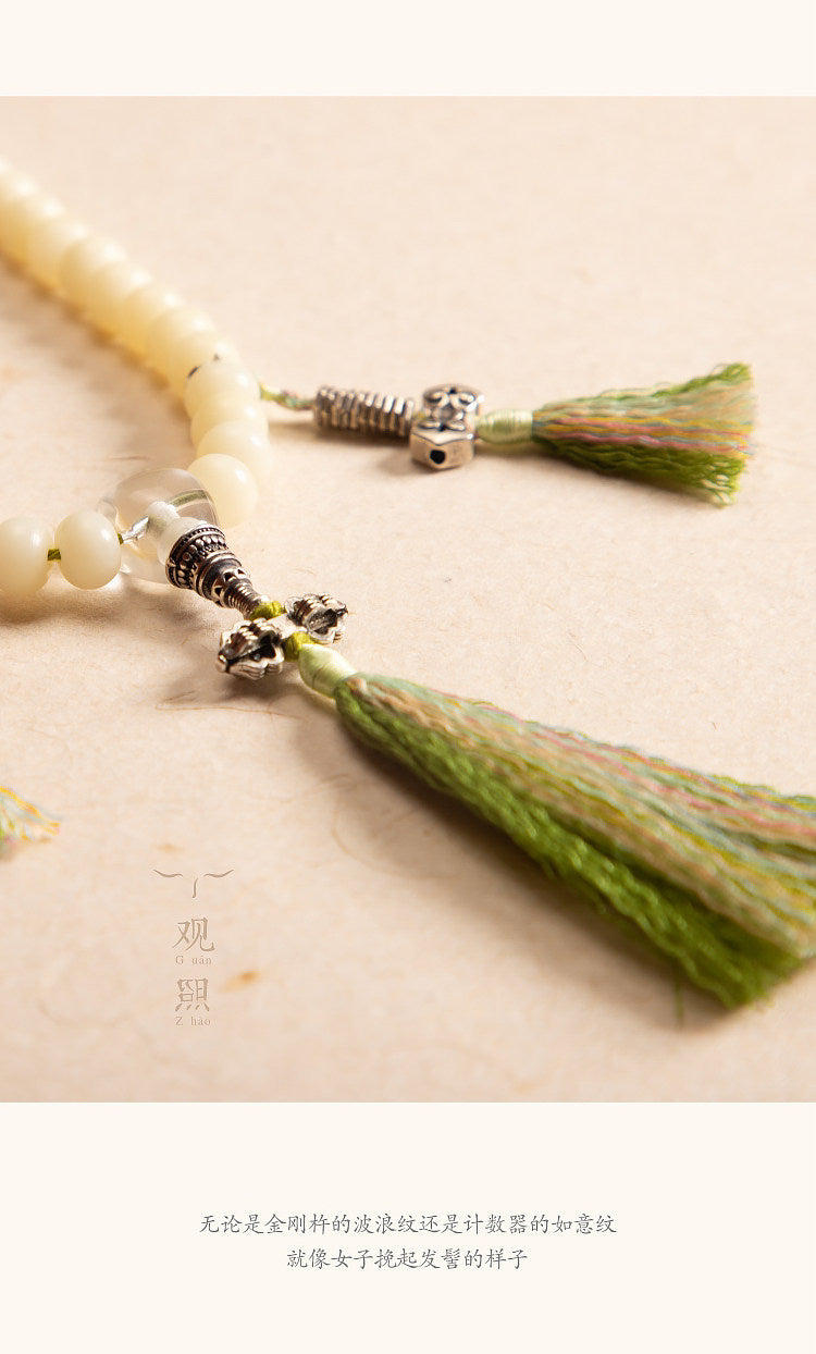 Close view of tassel and metal accent details on white bodhi mala