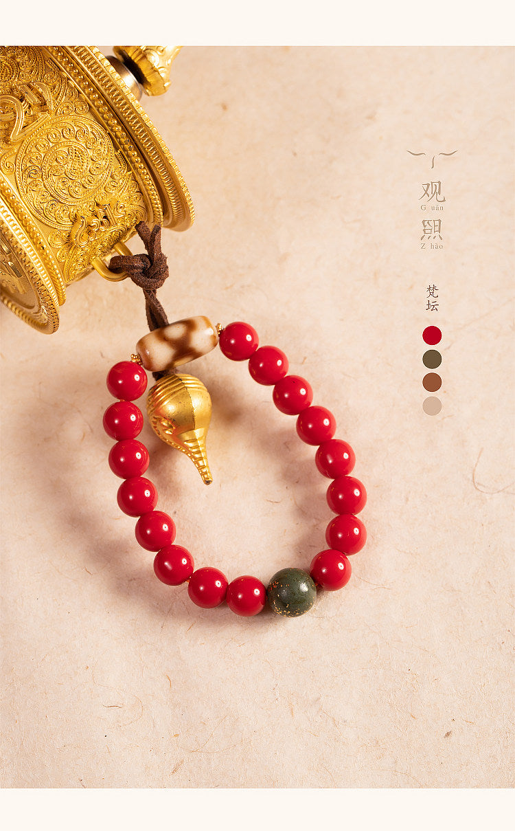Red glass bracelet beside a prayer wheel
