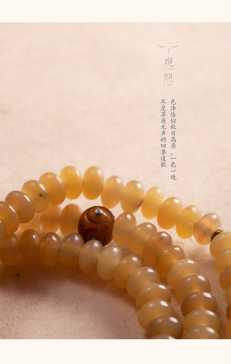 Close view of honey-yellow sheep horn mala beads and companion bead