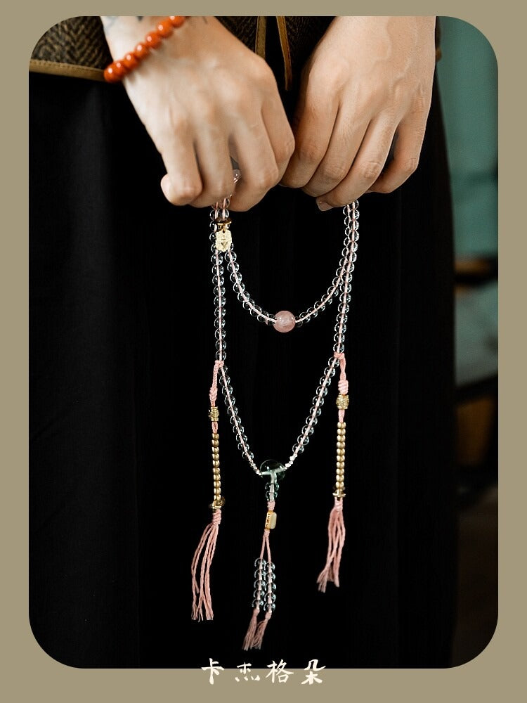 White crystal mala held as a necklace with tassel accents