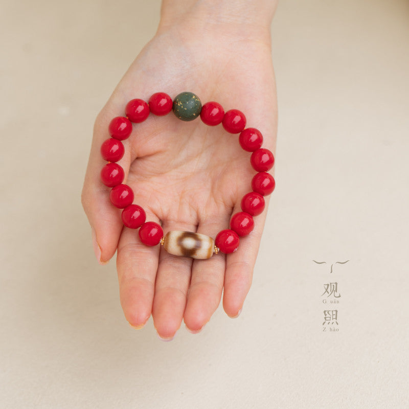Red glass bracelet with focal bead shown in hand