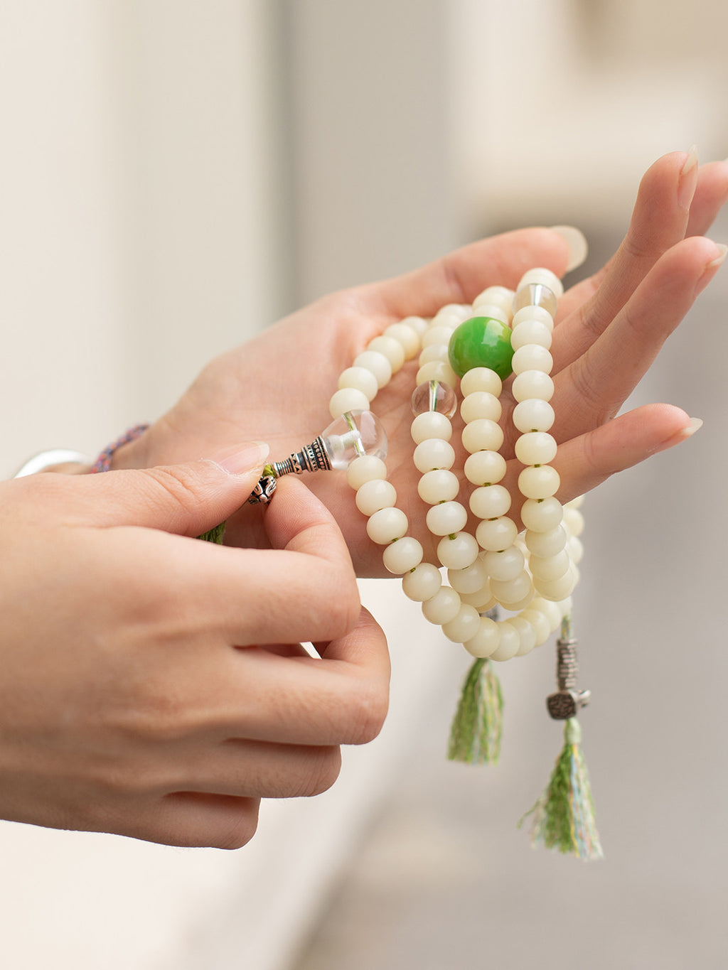 White bodhi mala with green accent bead held in hand