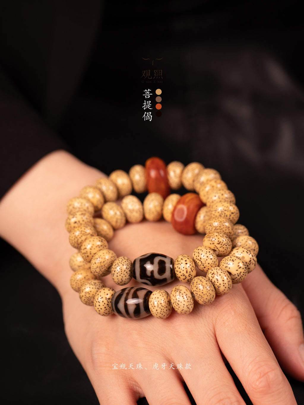 Xingyue bodhi bracelet with tiger-tooth dzi-style bead and red accent bead held in hand